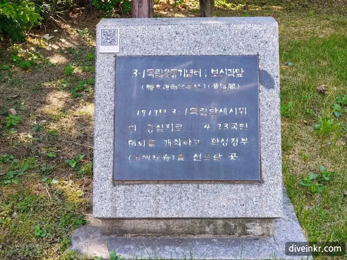 A granite memorial stone on the lawn in front of Bosingak with a dark metal plaque reading 3·1독립운동기념터 ; 보신각앞, followed by a short inscription in Korean with a few words in Chinese characters