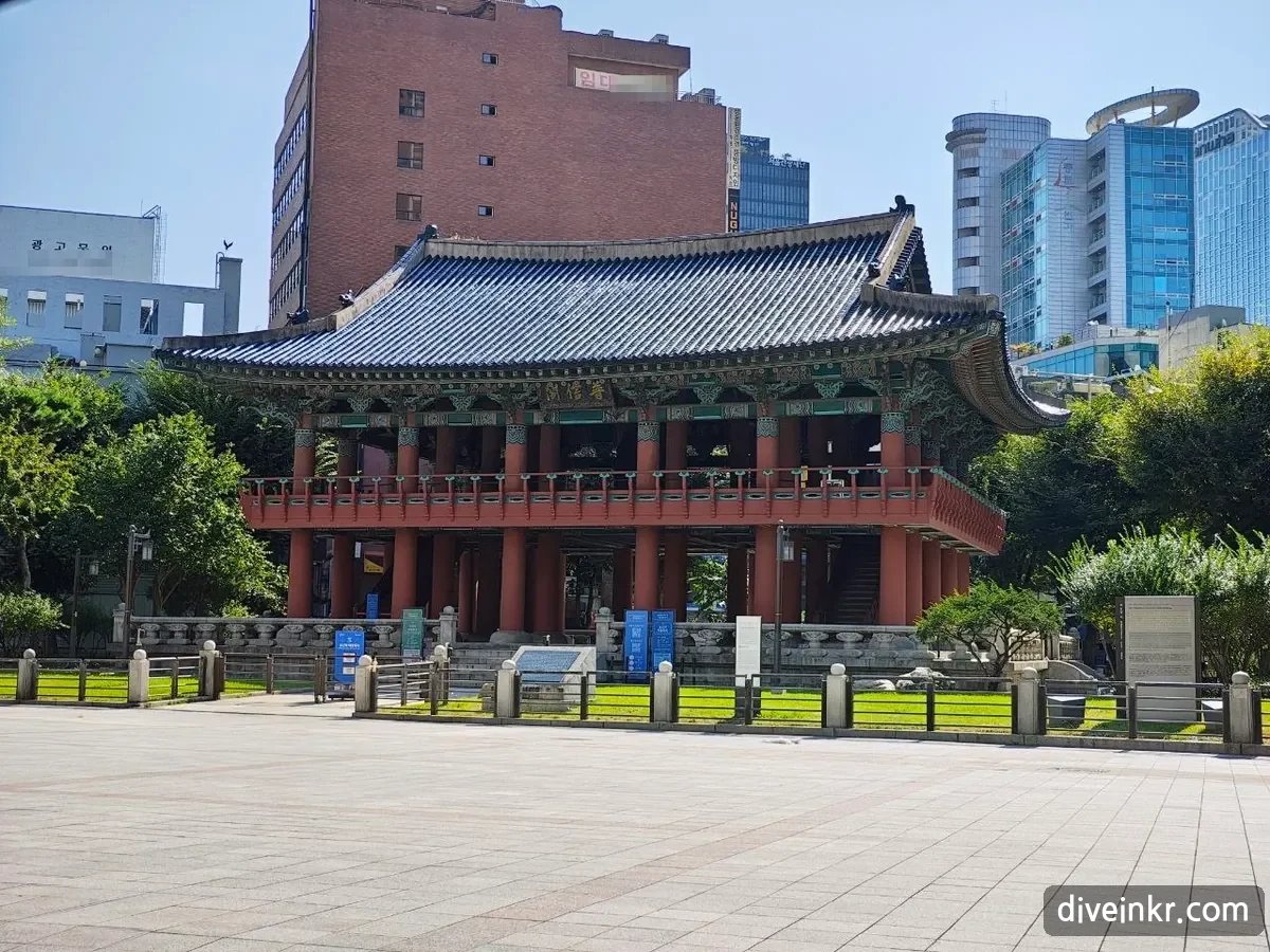 The Bosingak bell pavilion in Jongno with a traditional tiled roof, in front of a brick office building with a banner reading 임대 near the top, and a building on the left with a sign reading 광고문의 (phone numbers blurred)