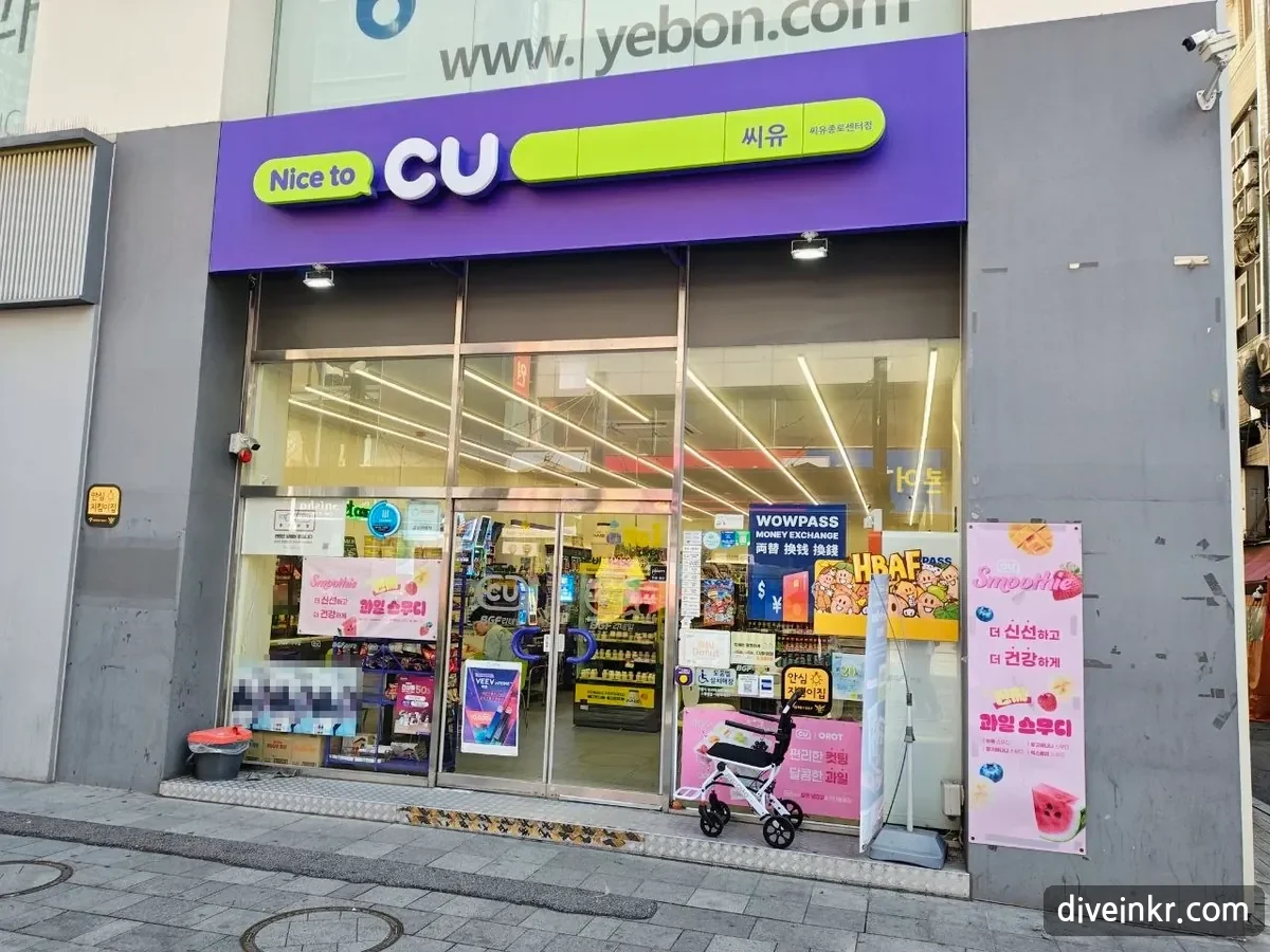 The front of a CU convenience store in Jongno with a purple-and-lime sign reading Nice to CU and, in smaller letters, 씨유 and 씨유종로센터점, glass doors covered with posters for fruit smoothies, a WOWPASS money exchange sticker and a 안심지킴이집 safety sticker (faces on posters blurred)