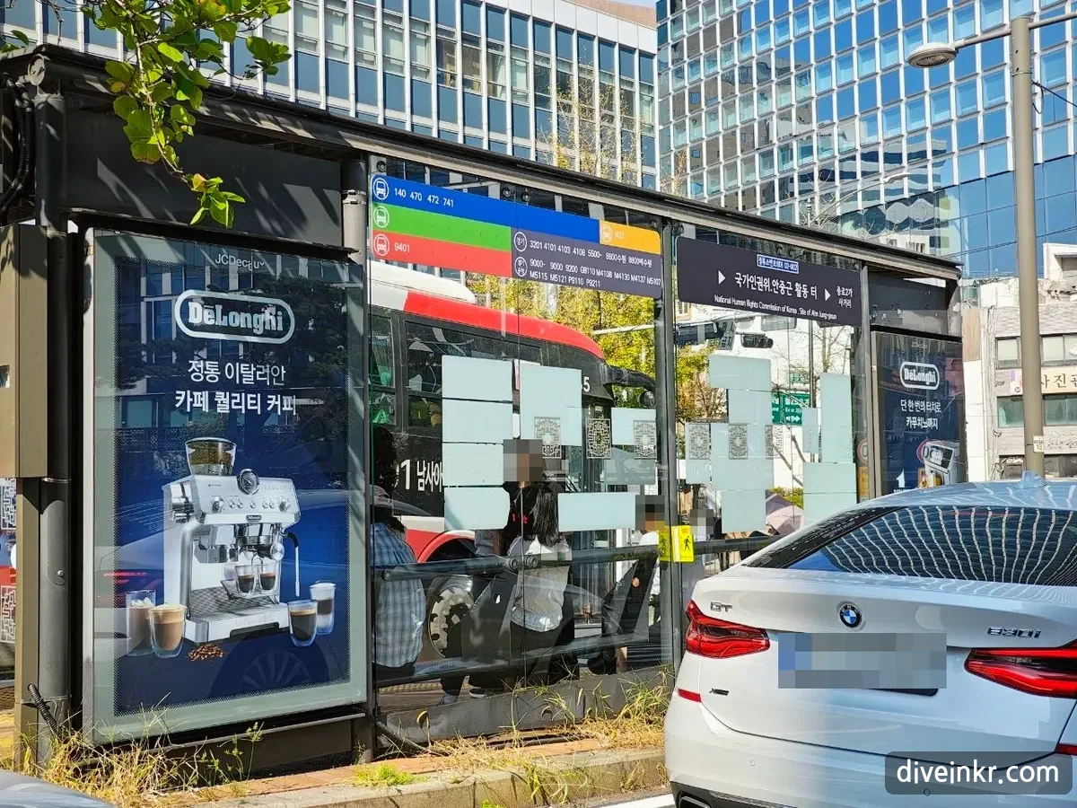 Colored route bands on a Seoul bus shelter: a blue band listing routes 140, 470, 472 and 741, a green band, a red band with route 9401, a yellow band with N37, and a gray panel marked 경기 listing Gyeonggi routes such as 3201, 5500, 9000 and M-routes (license plate of a parked car blurred)
