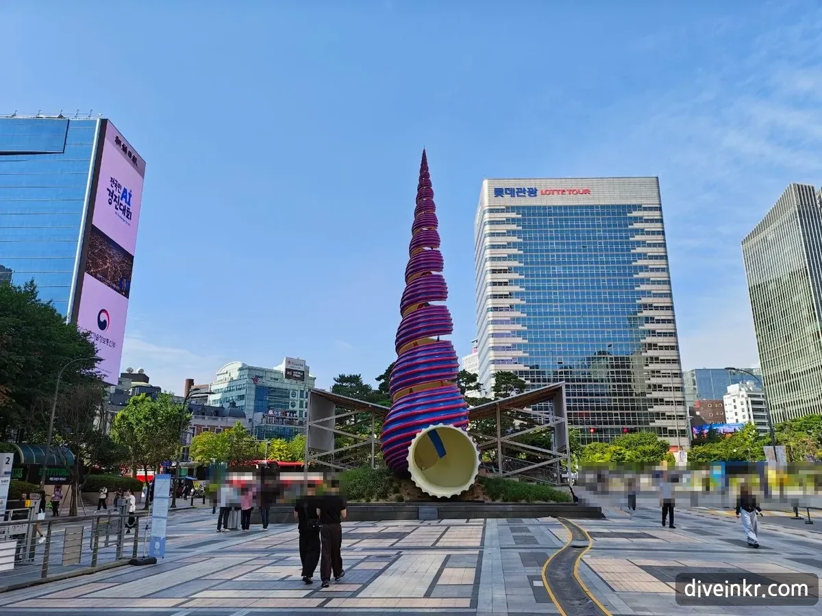 The Spring sculpture at Cheonggye Plaza: a tall spiral cone wrapped in red and blue ribbons, about 20 meters high, with a white opening at the base where the stream begins, among office towers (faces blurred)